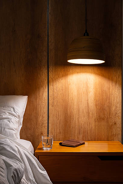 istock Bedside table with warm lamp glow, glass of water and notepad 2241283201