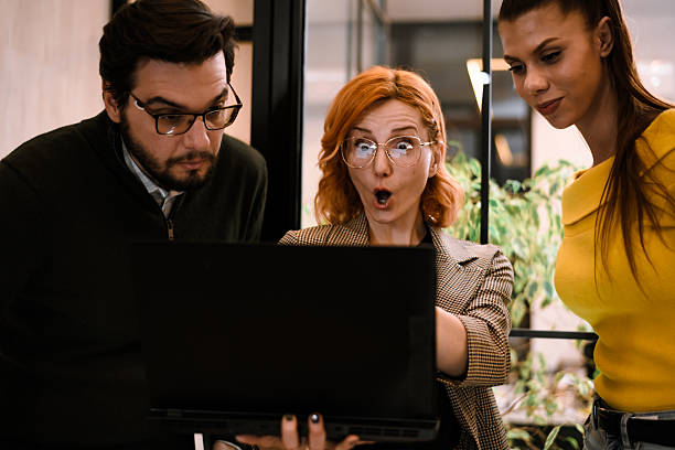 istock Three colleagues gather around a laptop in a modern office, expressing surprise and excitement over a presentation or data on the screen during a midday work session 2241286706