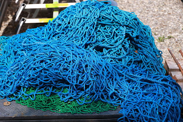 A pile of blue and green ropes. The blue rope is on top of the green rope. The pile is on a black surface