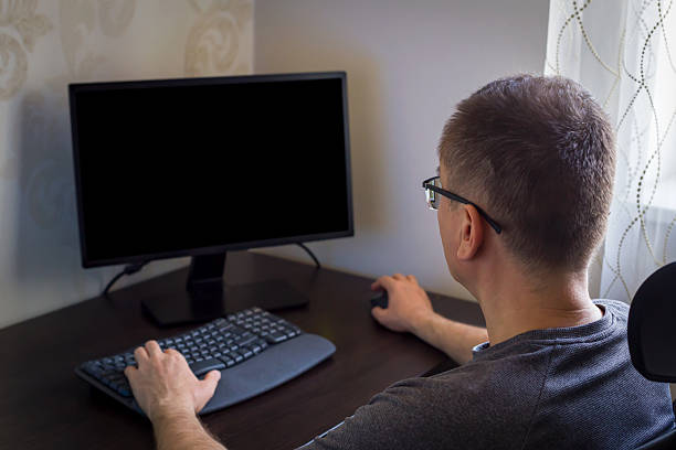 istock Man working at desk with computer monitor and keyboard in cozy home office setting 2241294204