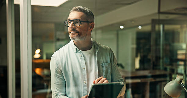 istock Thinking, night and business man on tablet for project ideas, planning and solution by window. Working late, creative and mature person with inspiration on tech for research, proposal and website 2241294503
