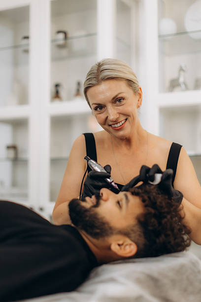 istock Professional beautician applying permanent makeup on man eyebrow 2241294573