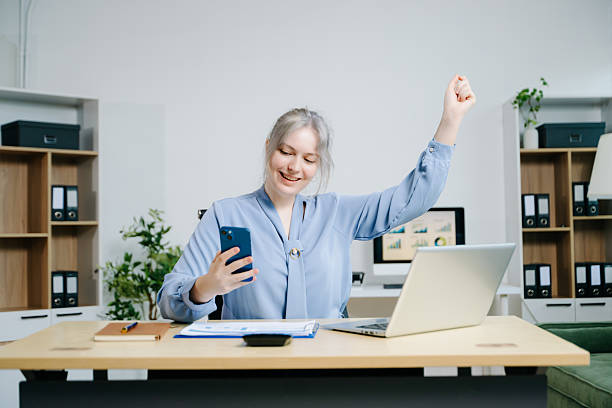 istock businesswoman celebrating success while analyzing reports in a modern office. Ideal for finance, accounting, achievement, statistics, and business growth themes. 2241294678