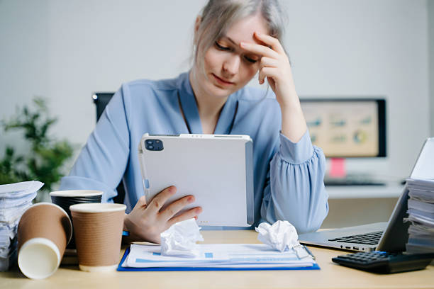 istock Exhausted businesswoman surrounded by documents and coffee cups, stressed from deadlines and workload. Ideal for burnout, corporate fatigue, and workplace pressure themes. 2241294757
