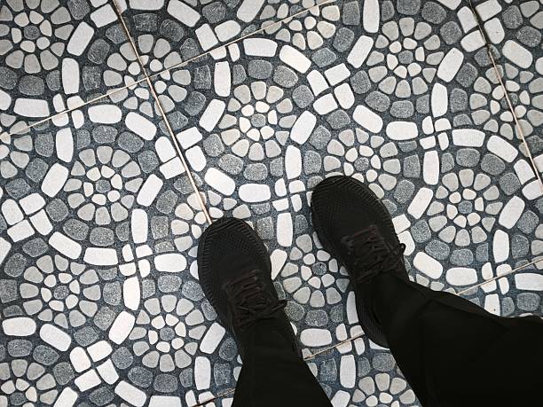 A person's feet standing wearing black shoes