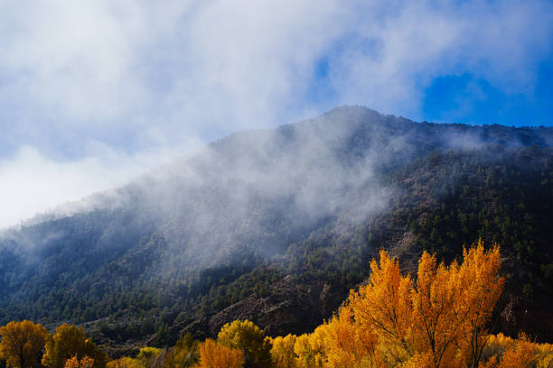 Scenic mountain view with haze and fog lifting and blue sky emerging with autumn leaf colors.