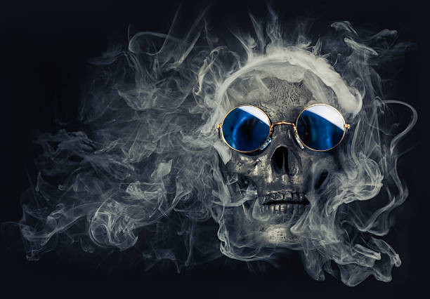 istock Old human skull wearing cool blue sunglasses and surrounded by wispy smoke 2241311316