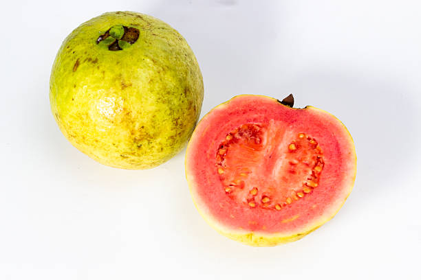 Fresh guava still life showcases one whole fruit and one sliced in half on white backdrop.