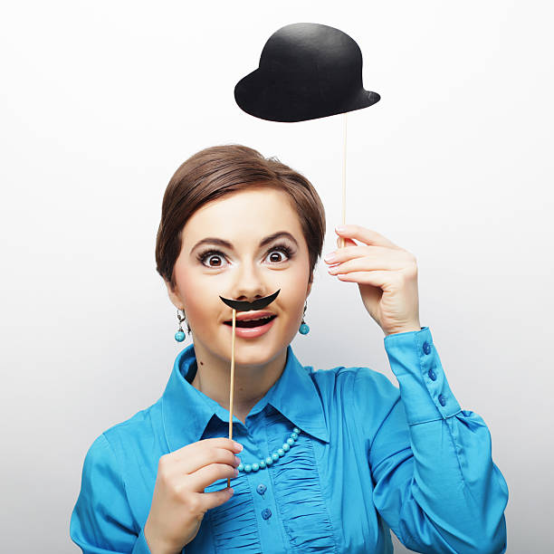Happy young girl posing with photo booth props hat on black background