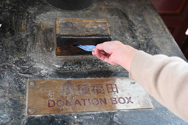 A woman dropping banknotes into a donation box inside a temple