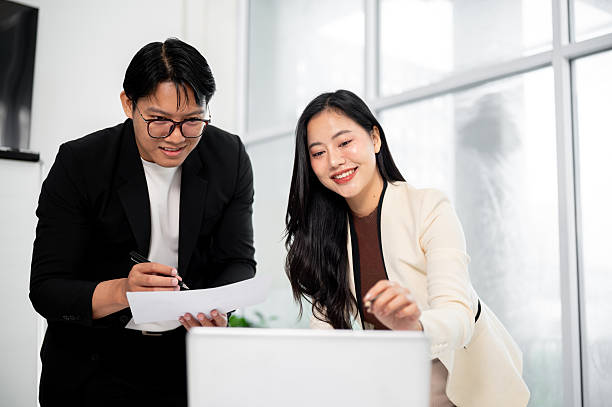 istock Businesswoman or office worker smiling while pointing on laptop to a man holding document over table 2241315626