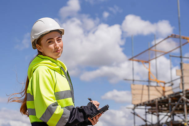 istock Portrait of builder woman using mobile device tablet with touchscreen on construction site 2241316698