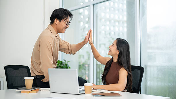 istock Businessman or office worker sitting on working table and clapping hands with a woman aside laptop. 2241316935
