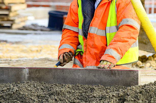 istock Close-up of construction worker leveling concrete and placing edging pin kerb on construction site 2241317222