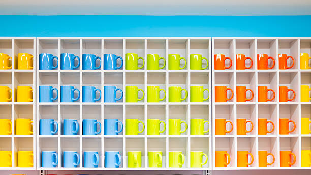 istock Colorful ceramic mugs arranged neatly in white square shelves with bright blue wall background, representing organization, kitchenware display, and modern interior decoration. 2241317520