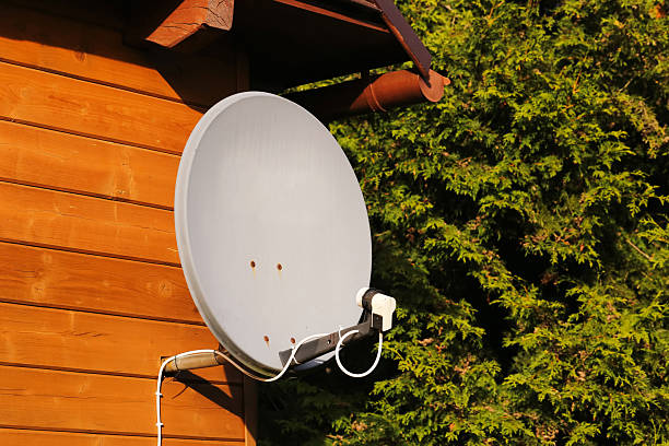 istock Satellite dish on wooden house wall. Communication technology equipment outdoors. Television signal receiver antenna closeup. 2241318739
