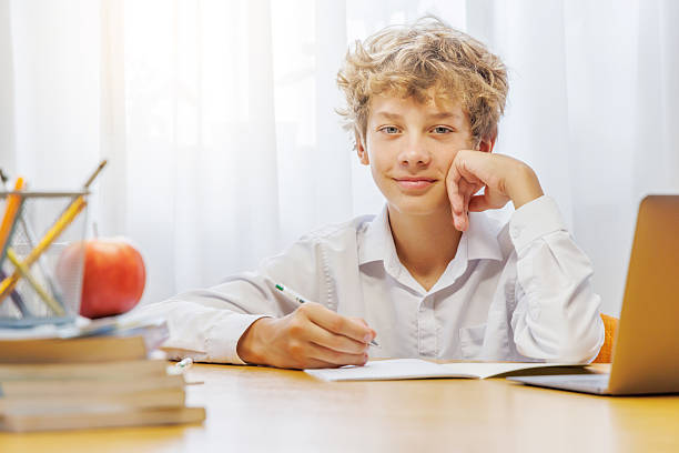 istock Schoolboy studying at home with laptop, notebook and learning materials 2241322411