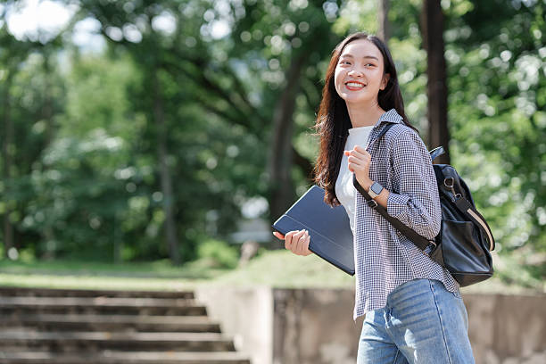 istock Young asian student walking on campus with laptop 2241324653