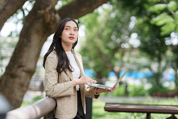 istock Woman using laptop outdoors, thinking about business solutions 2241324865