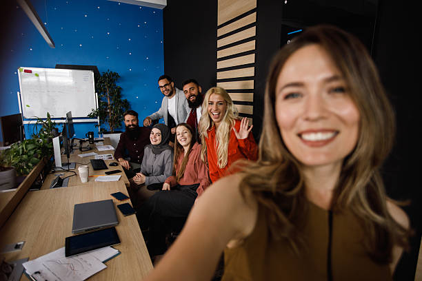 istock Diverse group of professionals smile for a selfie in a modern, collaborative office workspace 2241325064