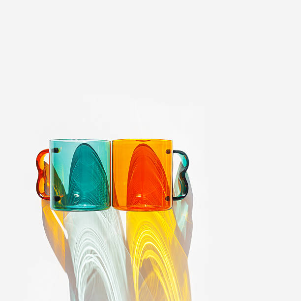 istock Orange and green Glass Mugs with bright sunlight Shadows, transparent cups casting dynamic, vibrant lights reflections and shadows on light white, creative aesthetic top view, minimal style, closeup 2241325955