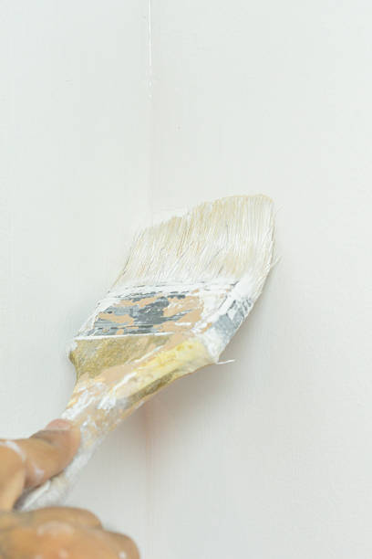 Close-up of a painter's hand using a paintbrush to \