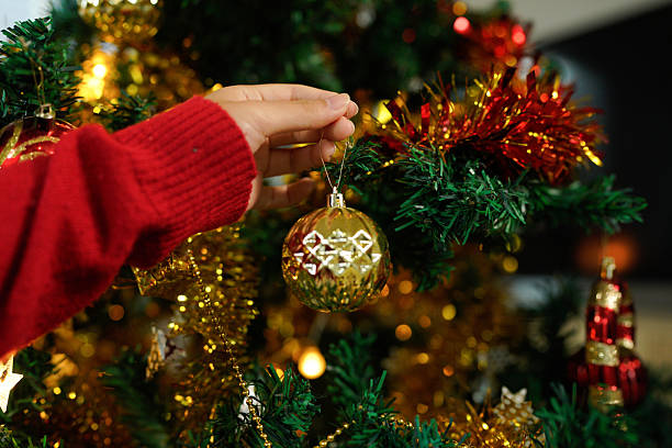 istock Hands decorating Christmas tree with ornaments and lights for festive holiday celebration 2241329069