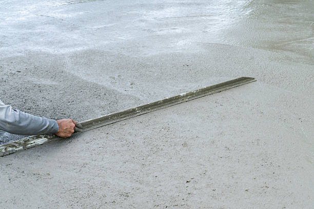 istock Construction Worker Screeding Wet Concrete Slab 2241331085