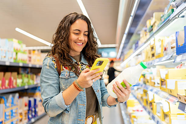 istock Woman comparing prices using mobile phone in supermarket 2241331935