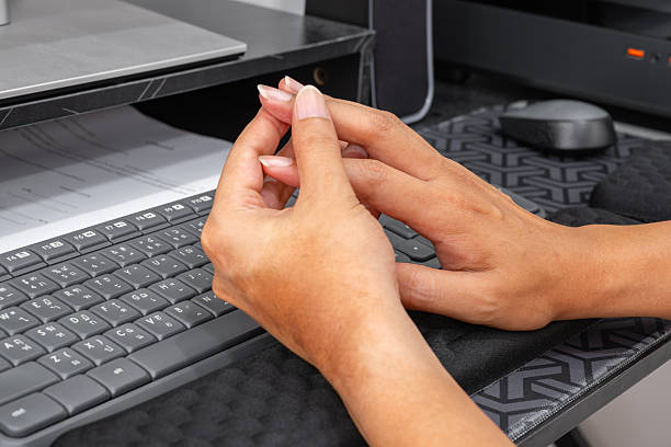 istock Interlocked fingers resting near keyboard—office fatigue. 2241332175