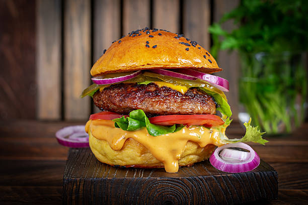 istock Beef hamburger. Sandwich with beef burger, tomatoes, cheese, pickled cucumber and red onions. Cheeseburger 2241334272