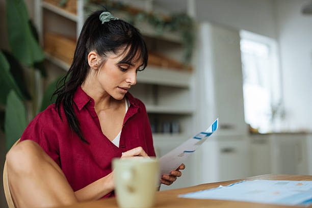 istock Woman managing household bills, checking financial documents at home 2241336725
