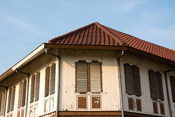 Stock image of a Dutch colonial building featuring traditional rooftop tiles and classic windows illuminated by warm afternoon sunlight. The architecture highlights elegant European colonial design under a bright blue sky, creating a timeless and historical atmosphere. Perfect for themes related to heritage architecture, historical tourism, and classic building aesthetics in tropical urban environments.