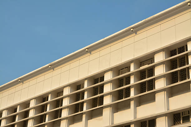 Stock image of a Dutch colonial building featuring elegant classic windows illuminated by warm afternoon sunlight under a clear blue sky. The image highlights the architectural charm and historical aesthetic of European-style colonial heritage found in Southeast Asia. Perfect for themes related to history, architecture, tourism, or cultural heritage preservation.