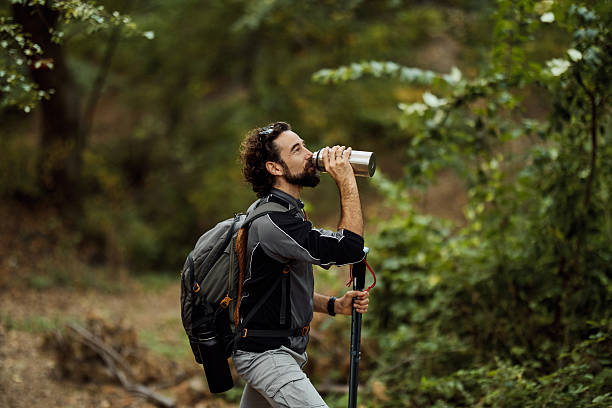 istock Man hydrating during active hike in green forest 2241337516