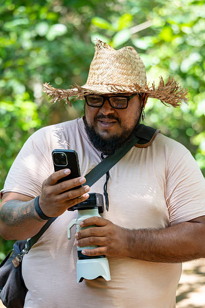istock Costa Rican nature photographer checking smartphone in tropical jungle, using camera 2241338146
