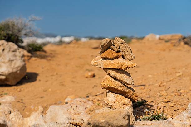 A man stands alone in a vast open desert. In front of him is a large stone cairn. Who is he, who built the cairn, and what does it all mean..? Who knows. \n\nScale model photography.
