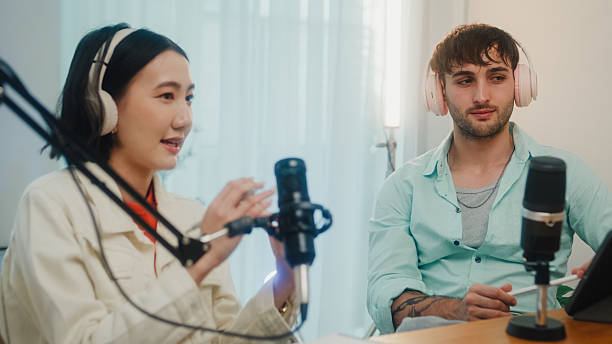 istock Generation Z podcasters collaborating wearing headphones discussing topics during recording session together in home studio. 2241342943