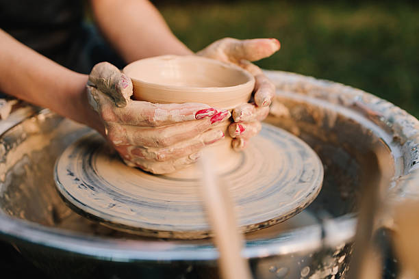 istock Potter shaping clay bowl on a wheel. Clay spins gently under hands as potter forms bowl. Clay molding on the wheel highlights pottery artistry and skill. 2241343585