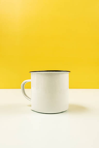 istock A white enameled metal mug on a smooth white surface with a yellow background 2241347519
