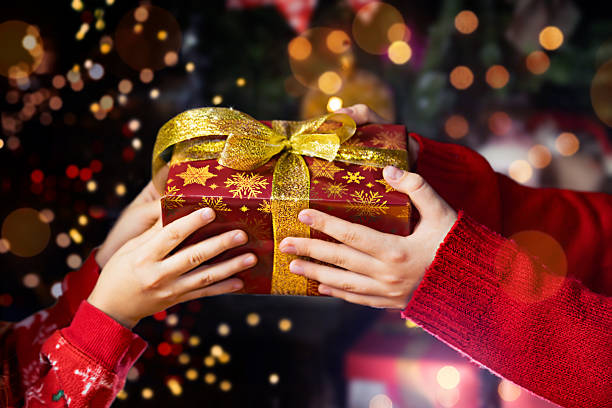 istock Christmas Gift Exchange – Hands Holding a Present with Golden Ribbon 2241350710