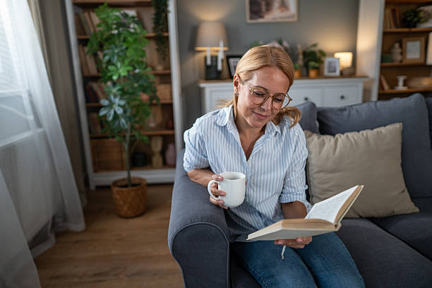 istock Woman relaxing at home, reading book, drinking coffee 2241351276