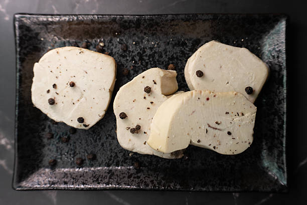 Seared foie gras delicacy, generously seasoned with coarse black pepper, creating a visually striking and rich texture contrast, ready for fine dining enjoyment