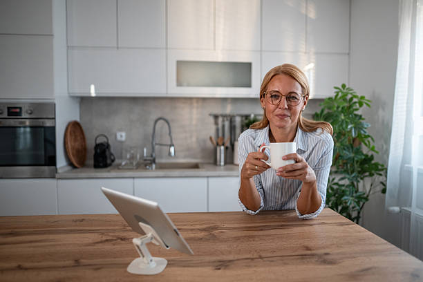 istock Mature woman enjoying coffee break with digital tablet in kitchen 2241352292