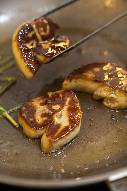 Sizzling pan-seared foie gras with fresh thyme sprigs in a hot skillet, creating a rich, aromatic French gourmet delicacy