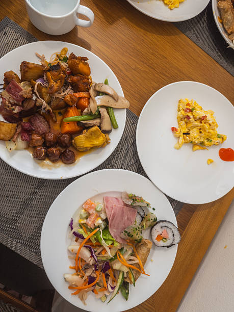istock An inviting overhead view of a diverse breakfast or brunch buffet spread featuring savory meats, fresh salads, scrambled eggs, and sushi rolls on a wooden table. A plentiful and delicious meal 2241355360