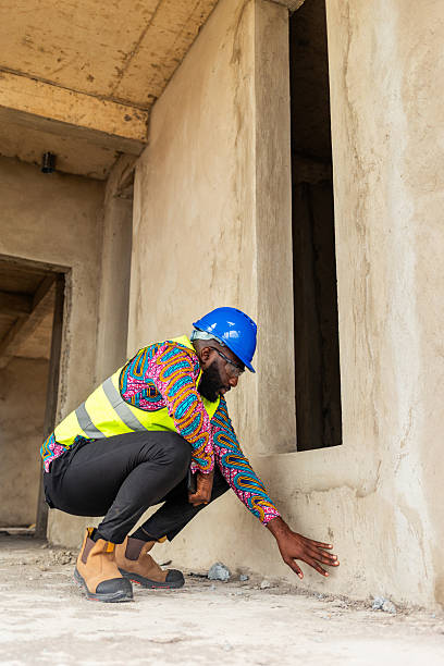 istock African construction engineer inspecting plaster on a building's wall at a site 2241357021