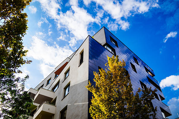 istock Modern residential building with reflective blue facade and geometric design under cloudy sky with bright light 2241357202