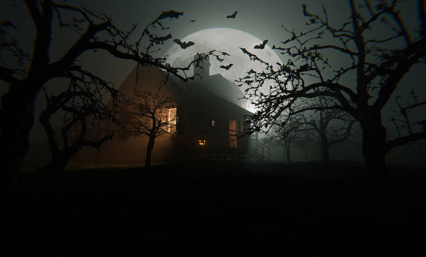 Old abandoned house with glow from windows with halloween pumpkin in field with trees with bats and forest with huge full moon on foggy scary night. Happy Halloween night, creative idea