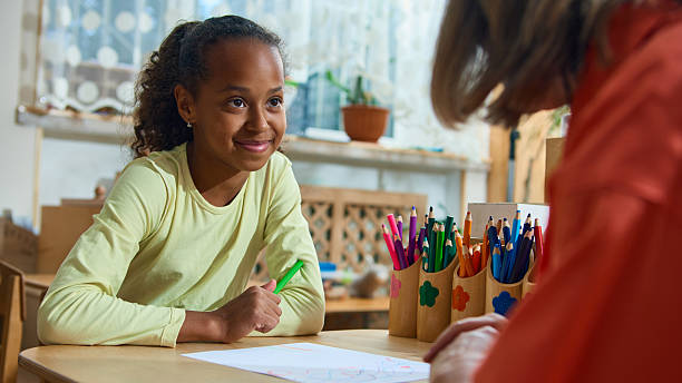 istock Young girl smiling at therapist during child counseling and creative activity session 2241359566